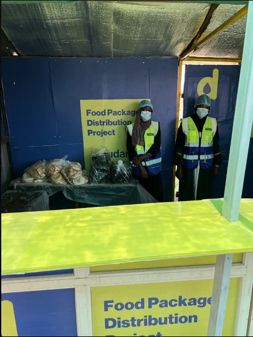 Droplets of Mercy Food Package Distribution Project booth with staff and bread in Sudan
